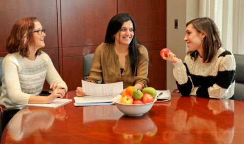 happy employees sitting at a table with fruit